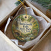 A round ornament with a scenic image of Buttermilk Falls State Park in New York, hanging from a string.