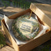 An ornament in a box, featuring a scenic landscape with a waterfall and lush greenery, with the text "Caledonia State Park, Pennsylvania" prominently displayed.