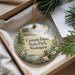A decorative ornament with a bird and a scenic landscape, hanging from a string.