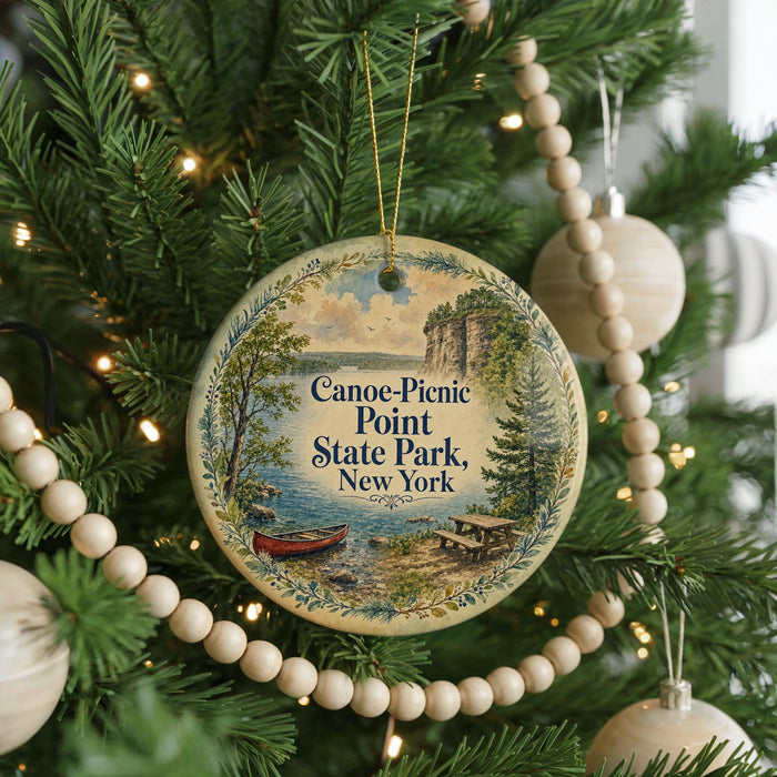 A round ornament on a Christmas tree, featuring a scenic image of Canoe-Picnic Point State Park in New York.
