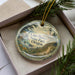A decorative ornament with a lighthouse and a scenic landscape, featuring the text "Cape Blanco State Park, Oregon".