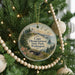 A round ornament hanging on a Christmas tree, featuring a scenic image of Cape Disappointment State Park in Washington.