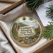 A decorative ornament with a scenic mountain landscape, featuring a bridge and a waterfall, is displayed in a box with pine branches.