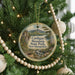 A round ornament hanging on a Christmas tree, featuring a scenic landscape with mountains, a lake, and a bridge.