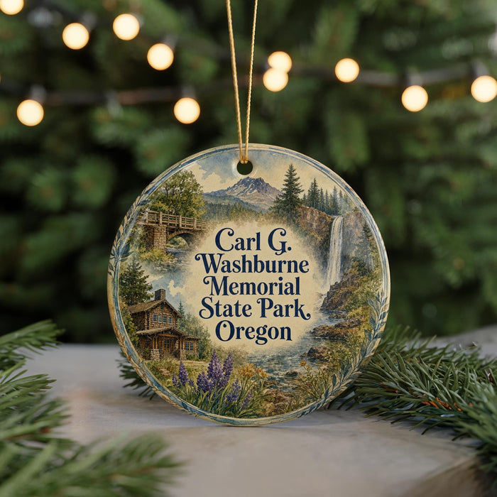A round ornament with a scenic landscape featuring a cabin, waterfall, and mountains, hanging from a string.