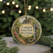 A circular ornament with a scenic image of a waterfall and a bridge, surrounded by greenery, hangs in front of a blurred background with twinkling lights.