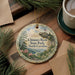 A decorative ornament featuring a scenic landscape of Chimney Rock State Park in North Carolina, with pine trees and a mountain in the background.