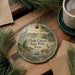 A decorative ornament featuring a scenic landscape of Choque Canyon State Park, Texas, with a deer and other wildlife elements. The ornament is placed on a wooden surface, surrounded by pine branches and a cup of coffee.
