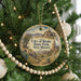 A round ornament hanging on a Christmas tree, featuring a scenic landscape with mountains and desert vegetation.