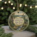 A round ornament with a scenic landscape of a forest, a waterfall, and a cabin, hanging on a string.