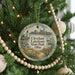 A round ornament hanging on a Christmas tree, featuring a scenic view of Cleveland, Ohio, with a lighthouse and a boat in the water.