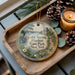 A wooden tray with a decorative ornament featuring a scenic view of Cold Spring Harbor State Park, New York, and pine cones.