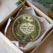 A decorative ornament in a box, featuring a scenic illustration of Coles Creek State Park in New York.