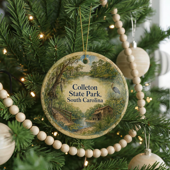 A round ornament hanging on a Christmas tree, featuring a scenic landscape with a bridge and a bird in flight.