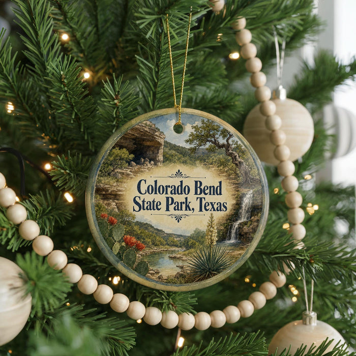 A round ornament hanging on a Christmas tree, featuring a scenic image of Colorado Bend State Park, Texas.