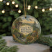 A decorative ornament featuring a scenic landscape with a mountain, river, and cabin, surrounded by pine trees and holiday lights.