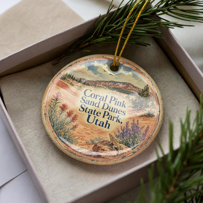 A decorative ornament with a landscape scene featuring a mountain, desert, and various plants, placed in a box with pine branches.