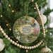A round ornament on a Christmas tree, featuring a portrait of a man and a scenic landscape.