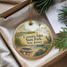 A decorative ornament with a lighthouse and a bird, placed in a box with pine branches.