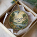 A decorative ornament in a box, featuring a scenic landscape with a lake, trees, and wildlife.