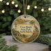 A round ornament with a painting of a windmill, a bird, and a rural landscape, hanging on a string.