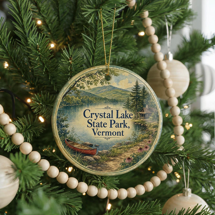 A round ornament hanging on a Christmas tree, featuring a scenic image of Crystal Lake State Park in Vermont.