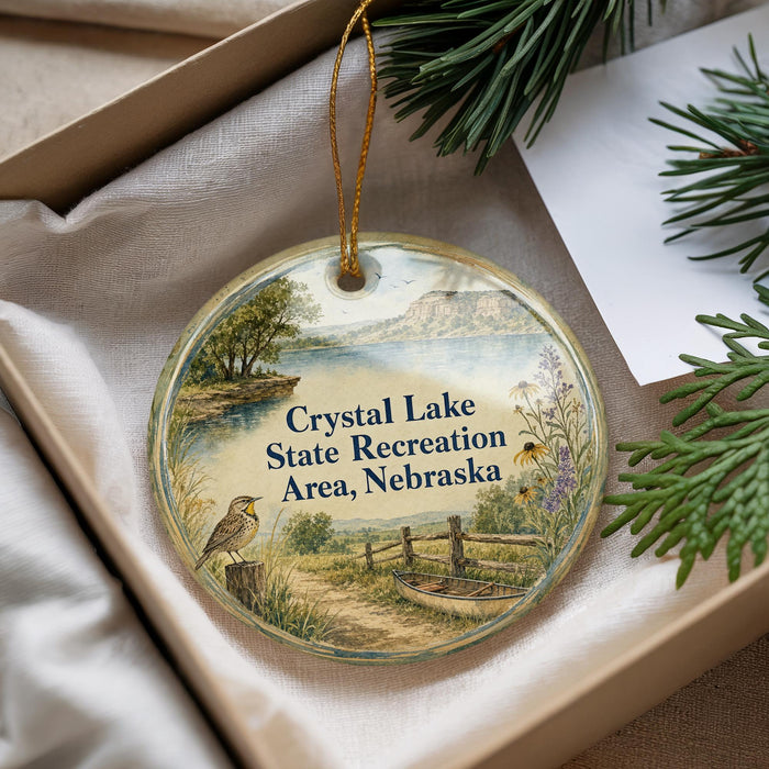 A decorative ornament with a landscape scene featuring a bird, a river, and a bridge, along with text that reads "Crystal Lake State Recreation Area, Nebraska".