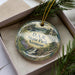 A decorative ornament in a box, featuring a scenic landscape with a waterfall and a castle, with the text "D.A.R. State Park, Vermont" printed on it.