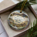 A decorative ornament in a box, featuring a scenic landscape with mountains, a windmill, and a small house, along with the text "Davis Mountains State Park, Texas".