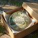 A decorative ornament in a wooden box, featuring a scenic image of the Delaware and Jersey Canal State Park in New Jersey.