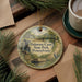 A decorative ornament featuring a scenic image of Delaware Canal State Park, Pennsylvania, with a bird in the foreground and pine branches surrounding it.