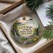 A round ornament with a scenic landscape of a waterfall, path, and flowers, hanging from a string.