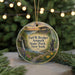 A circular ornament featuring an illustration of a scenic landscape with a waterfall, path, and various plants, hanging from a string.