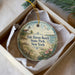 A decorative ornament in a box, featuring a lighthouse and a beach scene, with the text "Fair Haven Beach State Park, New York" on it.