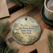A decorative ornament with a lighthouse and beach scene, featuring the text "Fair Haven Beach State Park, New York" on it, is displayed on a wooden surface alongside a cup of coffee and some pine branches.