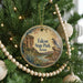 A round ornament hanging on a Christmas tree, featuring a scenic landscape of a cliff, river, and desert.