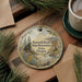 a round ornament with a scenic landscape, including a lake, mountains, and pine trees, hanging on a wooden surface. The ornament has a message that reads " Farewell Bend State Recreation Area, Oregon".