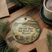 A decorative ornament featuring a house and a wagon, with the text "Felix Valle House State Historic Site, Missouri" printed on it. The ornament is placed on a wooden surface, surrounded by pine branches and a cup of coffee.
