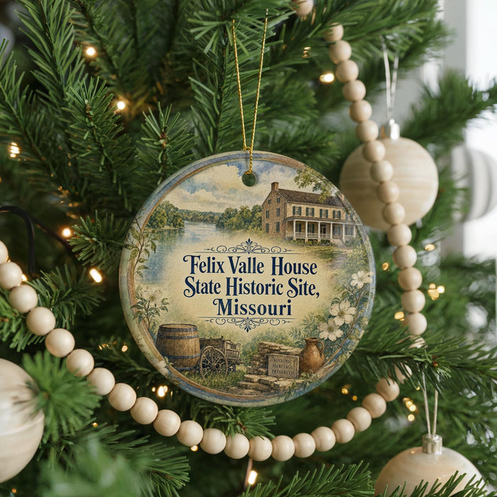 A round ornament hanging on a Christmas tree, featuring an illustration of a historic house and a river.