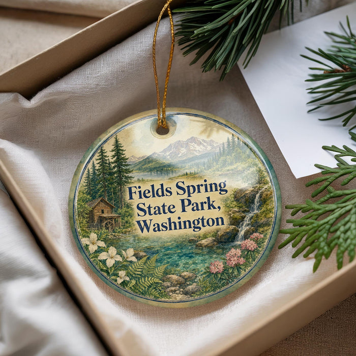 A decorative ornament with a scenic landscape of mountains, forests, and a waterfall, featuring the text "Fields Spring State Park, Washington".