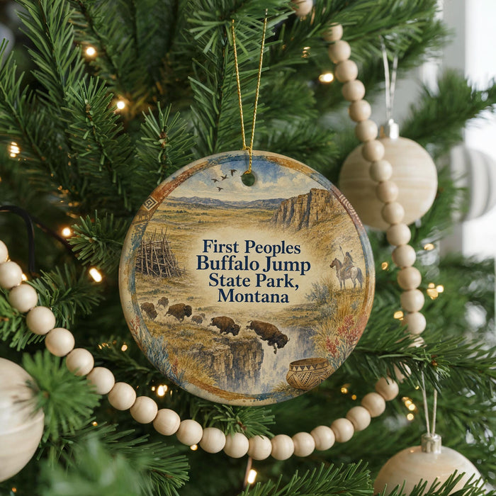 A Christmas tree decorated with ornaments, including a circular ornament with a scenic image of buffalo jumping over a river and the text "First People, Buffalo Jump State Park, Montana".