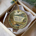 A round ornament with a scenic illustration of Fisher Grove State Park in South Dakota, featuring a bridge, pine trees, and a lake.