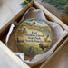 A decorative ornament in a box, featuring an illustration of Fort Abraham Lincoln, State Park, and North Dakota.