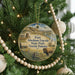 A round ornament hanging on a Christmas tree, featuring a scenic image of Fort Abraham Lincoln, State Park, and North Dakota.