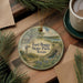 A round ornament with a scenic illustration of Fort Bogy State Park, Texas, hanging on a wooden surface.