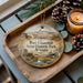 A wooden tray with a decorative ornament featuring an illustration of Fort Churchill State Historic Park, Nevada, and pine cones.