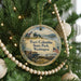 A round ornament hanging on a Christmas tree, featuring a scenic image of Fort Columbia State Park in Washington.