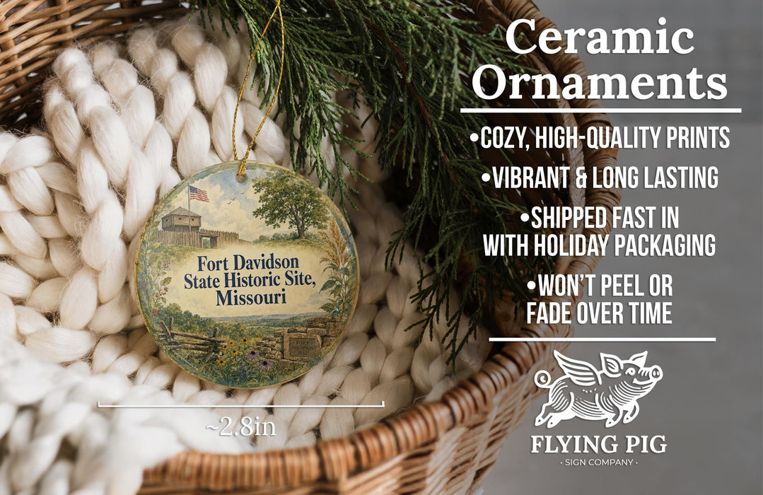 Ceramic ornaments, specifically a Fort Davidson State Historic Site, Missouri ornament, are displayed in a woven basket. The ornament features a tree and a building, and is described as a cozy, high-quality print with vibrant and long-lasting colors. It is shipped fast in holiday packaging and does not peel or fade over time. The image is a size 2.8in in diameter, and it is from the Flying Pig Sign Company.