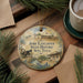 A decorative ornament featuring the Fort Lancaster State Historic Site in Texas, with a cannon and other historical elements, is displayed on a wooden surface alongside a cup of coffee and some pine branches.
