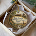 A circular ornament with a painting of a historical site, specifically Fort Leaton, Texas, displayed in a box.